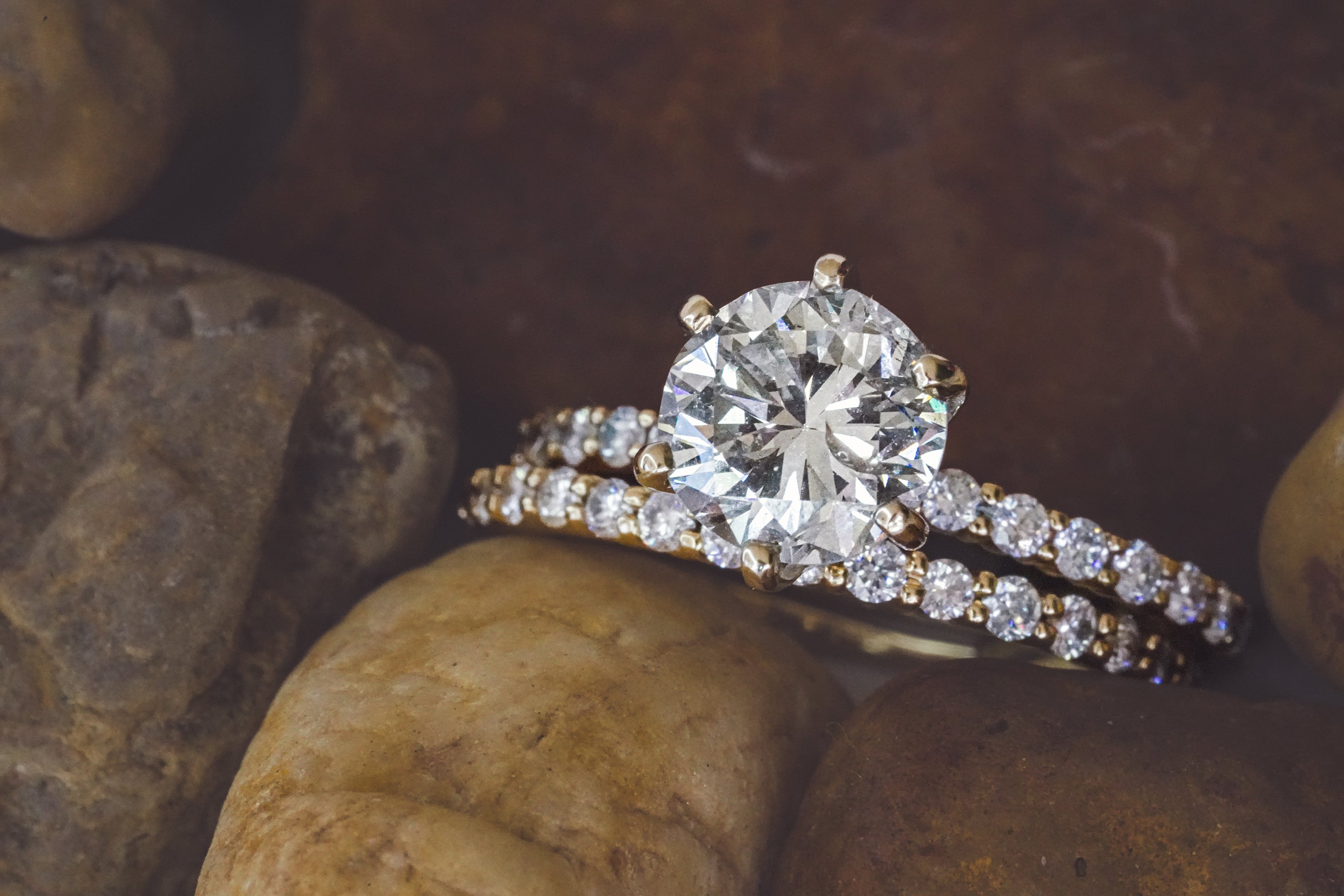 Gold bridal set featuring a round brilliant-cut solitaire engagement ring with a diamond-studded band, paired with a matching pavé wedding band